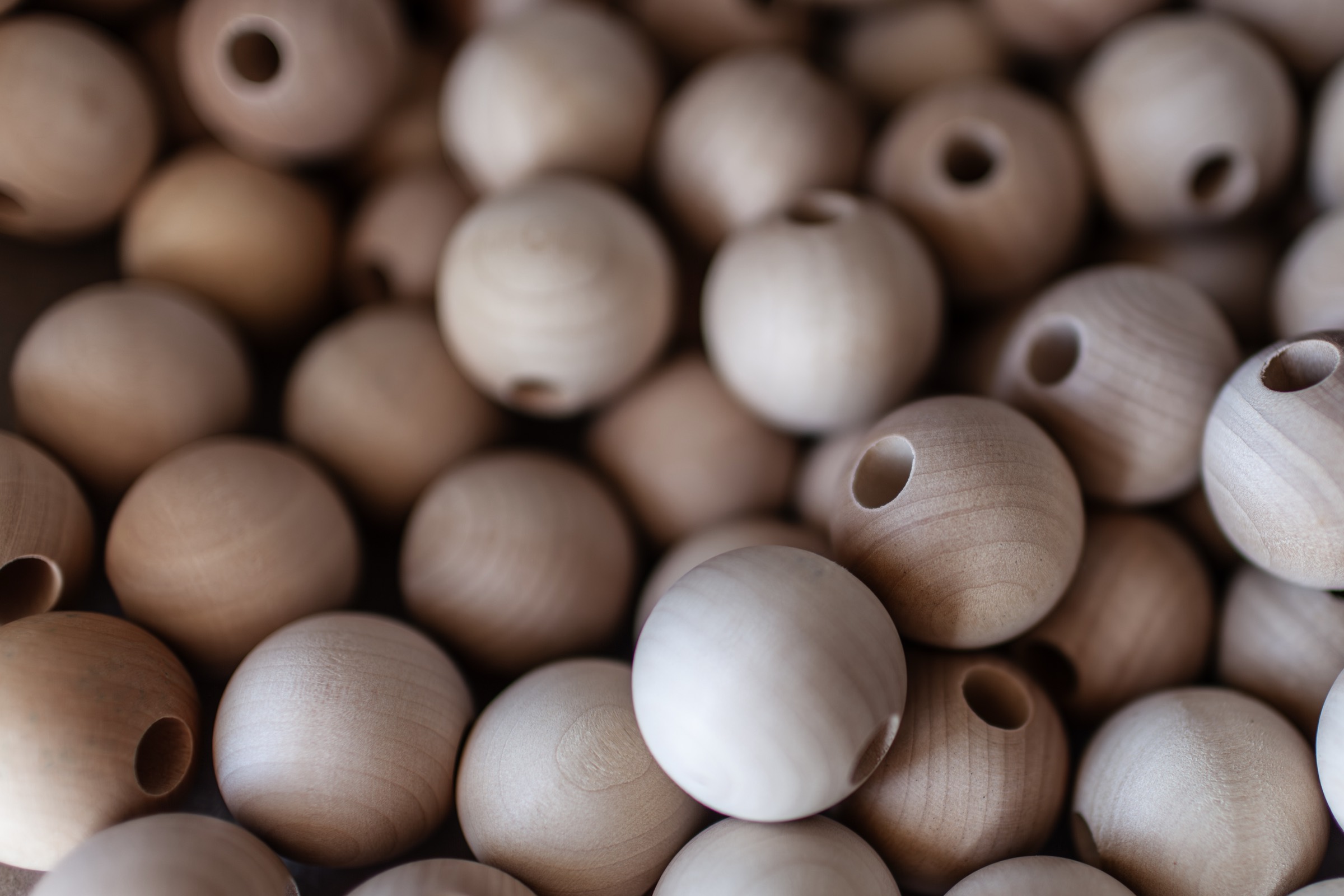 Unpainted wooden beads, each drilled through the center